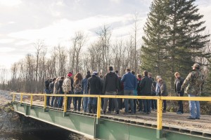 The group stands on the temporary bridge that was built two years ago. A permanent bridge is being constructed and will connect Freedom Road, which will join Hwy. #1 to the west of Shoal Lake 40. (photo credit: James Christian Imagery)