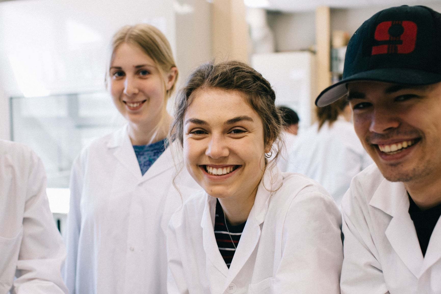 students in classroom smiling wearing white lab coats