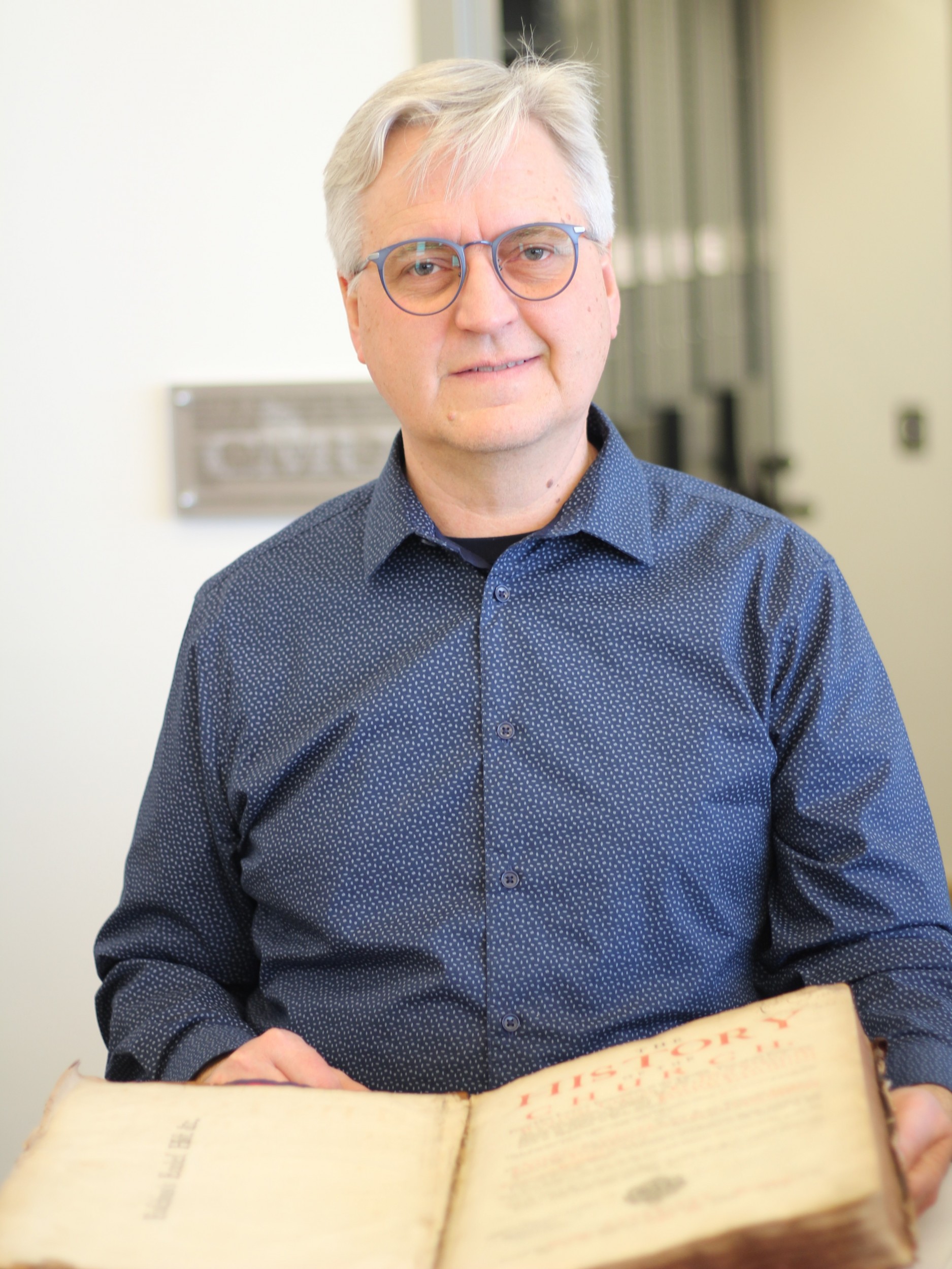 Professor of English Paul Dyck shows off one of the books from the rare book collection