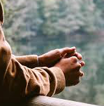 Hands folded together looking over a bridge