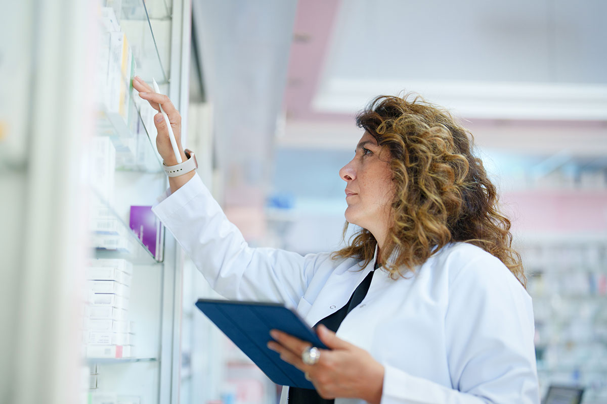A pharmacist takes stock of medicine on a shelf