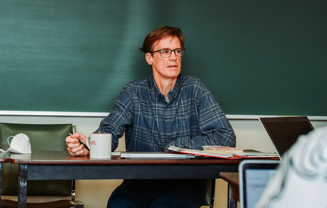Ray Vander Zaag sits at a desk at the front of a classroom