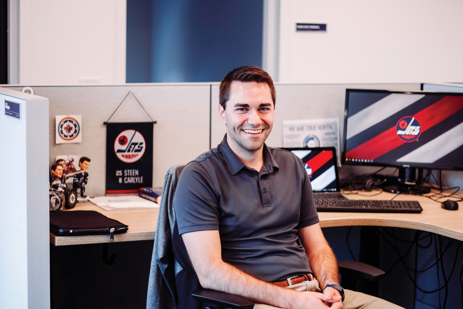 a man sits in a cubicle surrounded with Winnipeg Jets paraphernalia