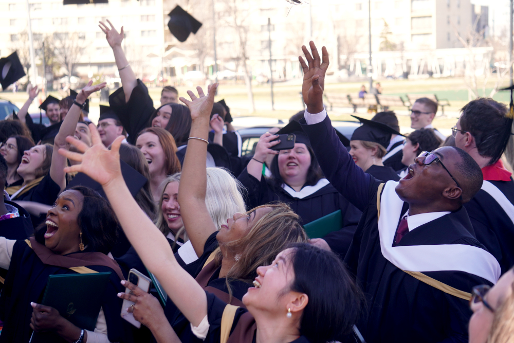 Grads throw their caps up outside after Convocation