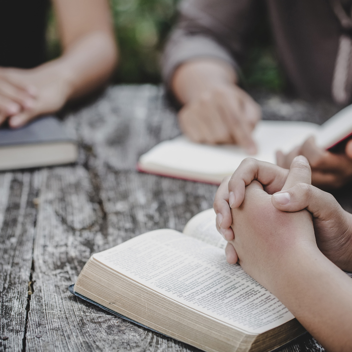 Hands praying over a Bible